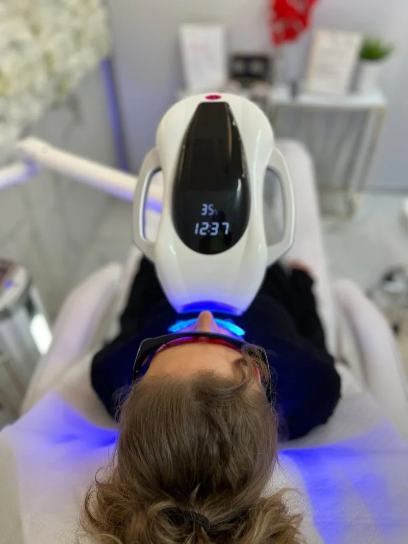 LED-Bleaching-Lampe über einer Kundin während der Behandlung